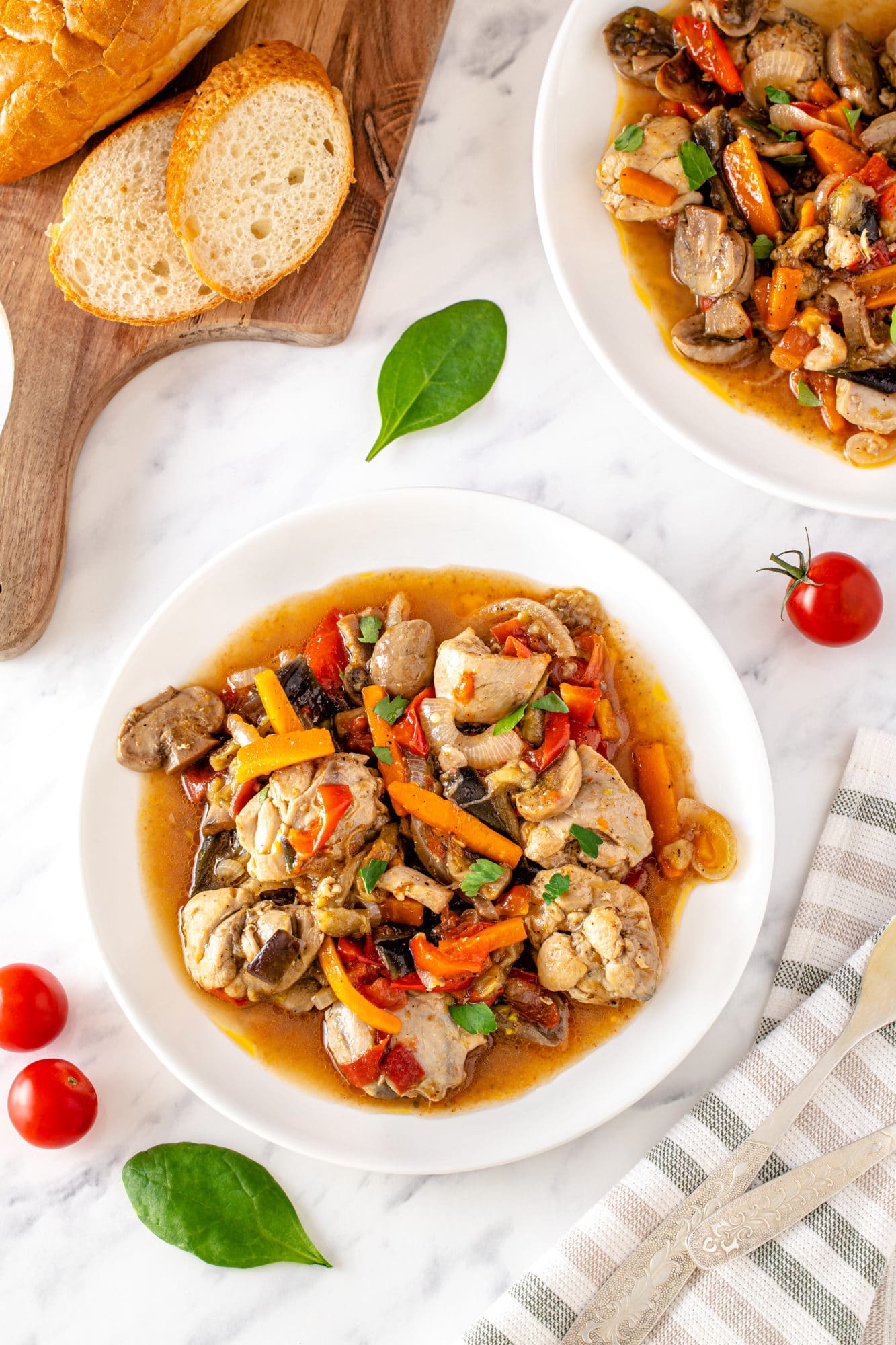 white-shallow-plate-with-skinless-boneless-chicken-thighs-with-olive-oil-sliced-carrots-on-white-surface-cherry-tomatoes-basil-leaves-slices-of-bread