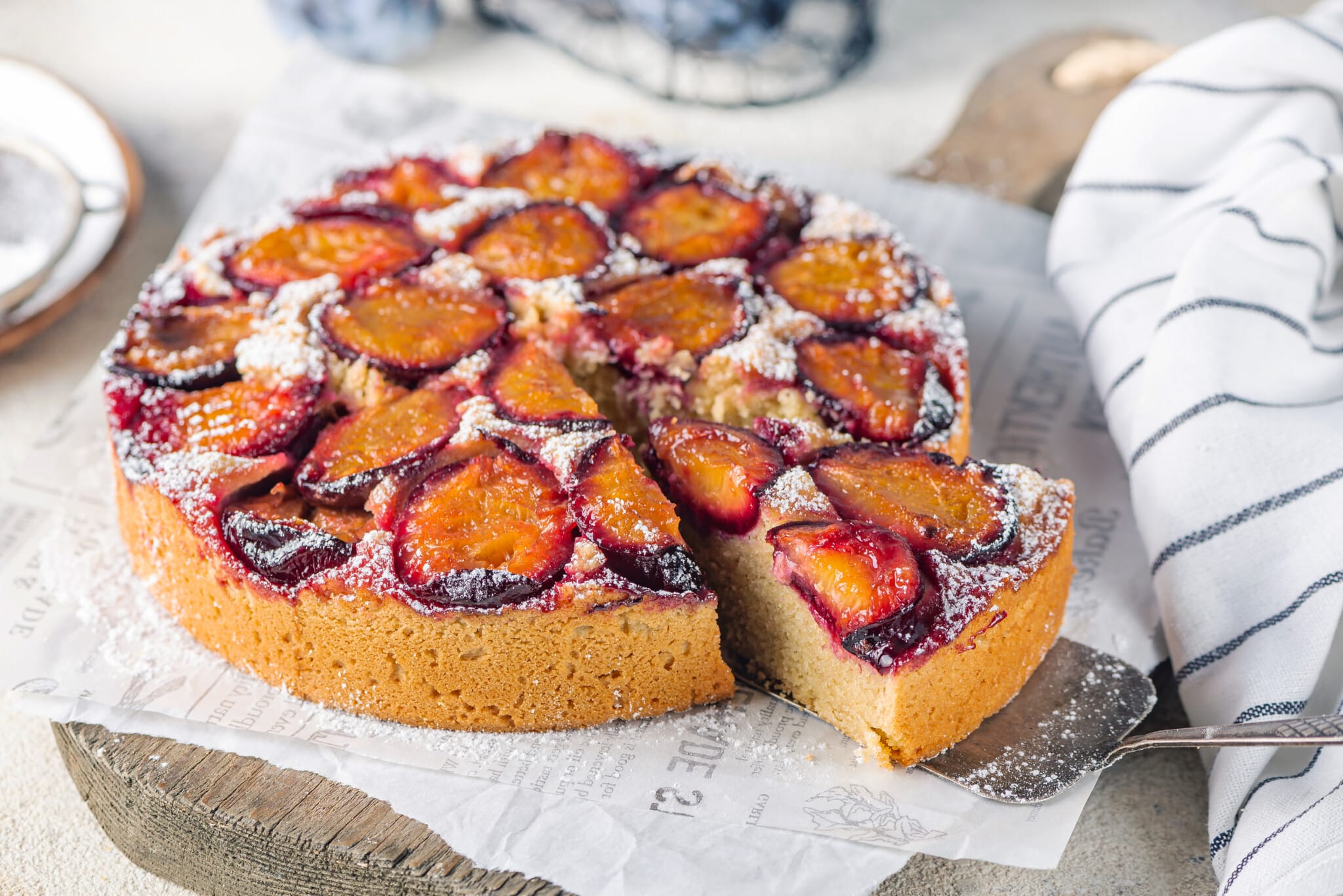 plum cake on white paper with a slice cut.