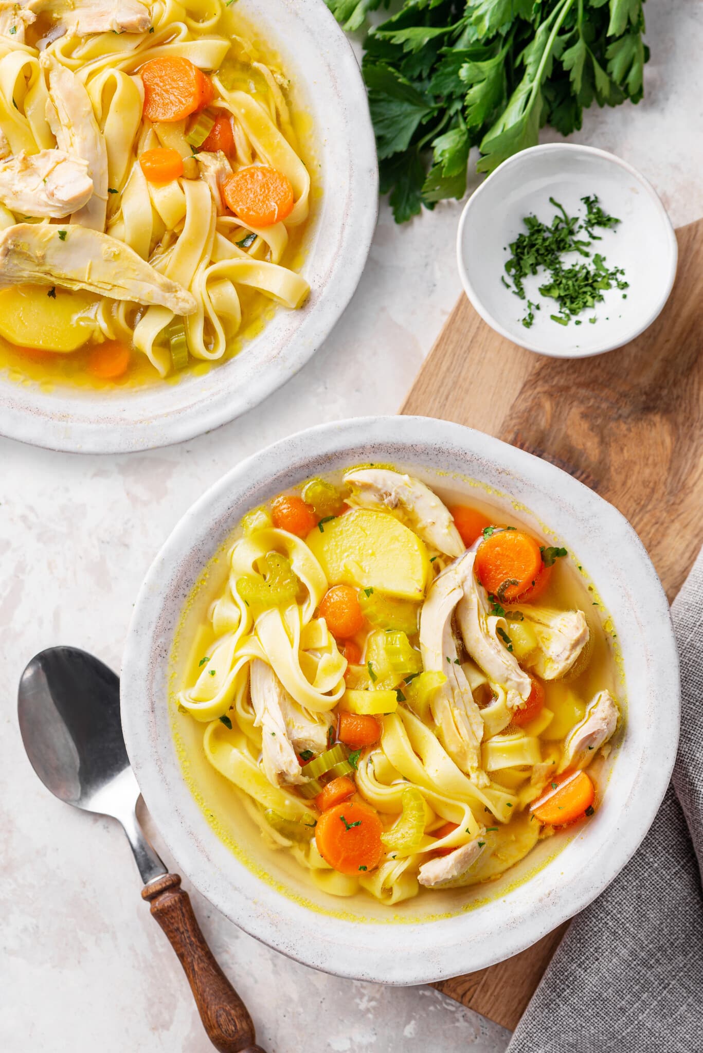 chicken-soup-in-a-white-bowl-on-a-wooden-board-with-a-spoon