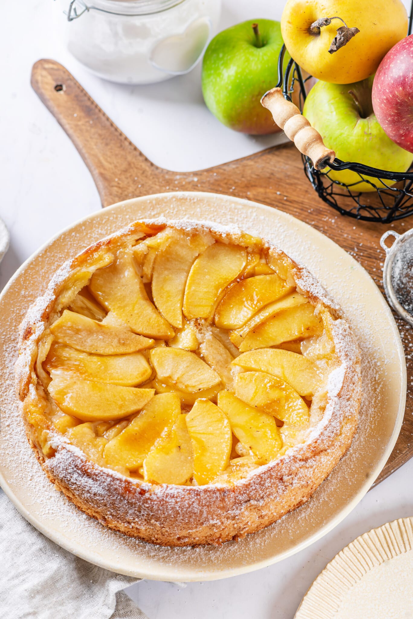 Apple cake on a white plate, on a wooden cutting board.