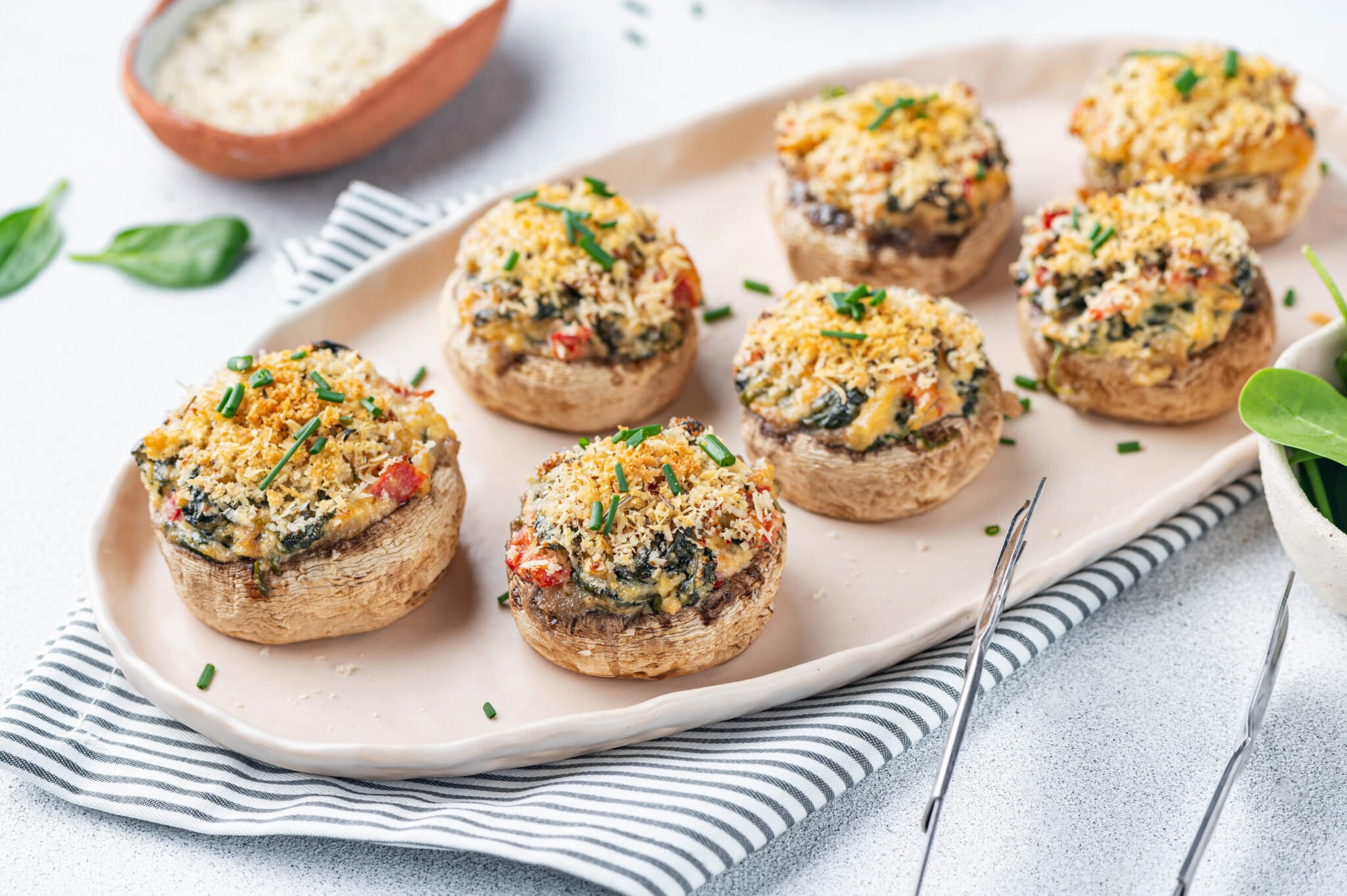 a striped towel with a beige plate on it and stuffed mushrooms prepared.