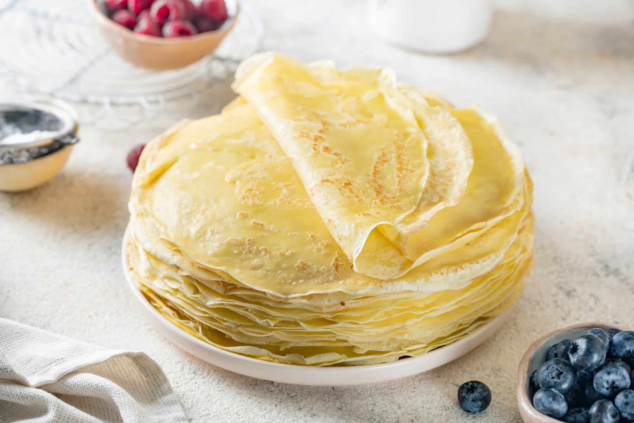 a stack of crepes on a plate with the top crepe folded over.