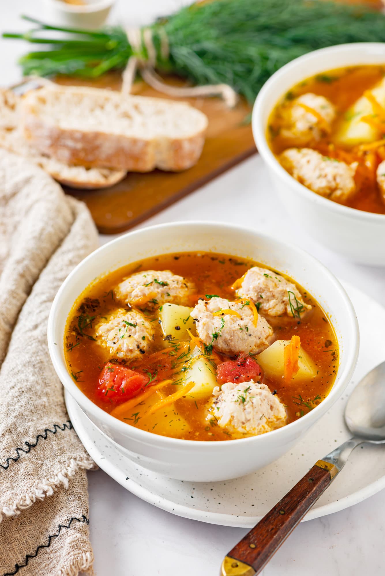 tomato-chicken-soup-in-a-white-bowl-on-a-white-plate-with-a-spoon