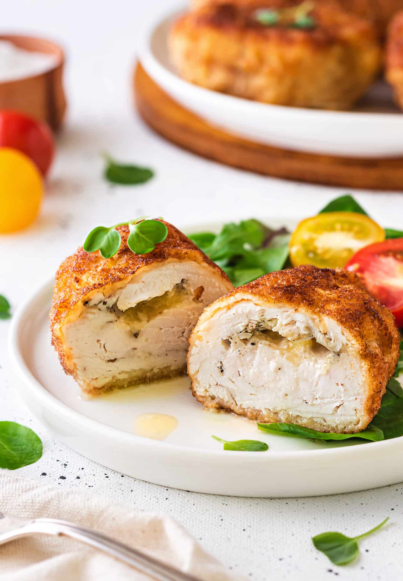 a white plate with halved stuffed chicken breast and microgreens.