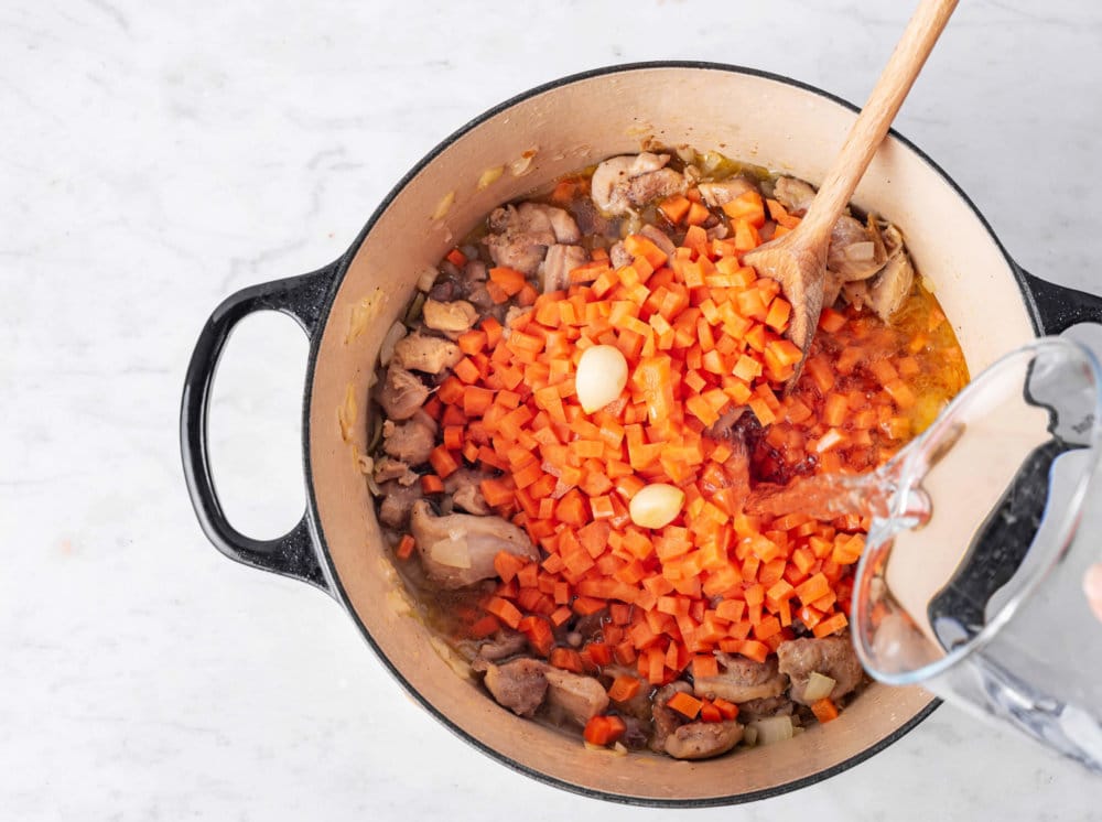 Adding water to chicken and carrots for plov.