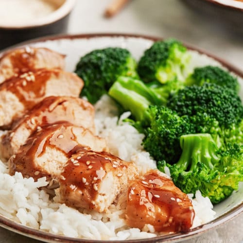 Sliced teriyaki chicken on a bed of rice, with broccoli on the side.