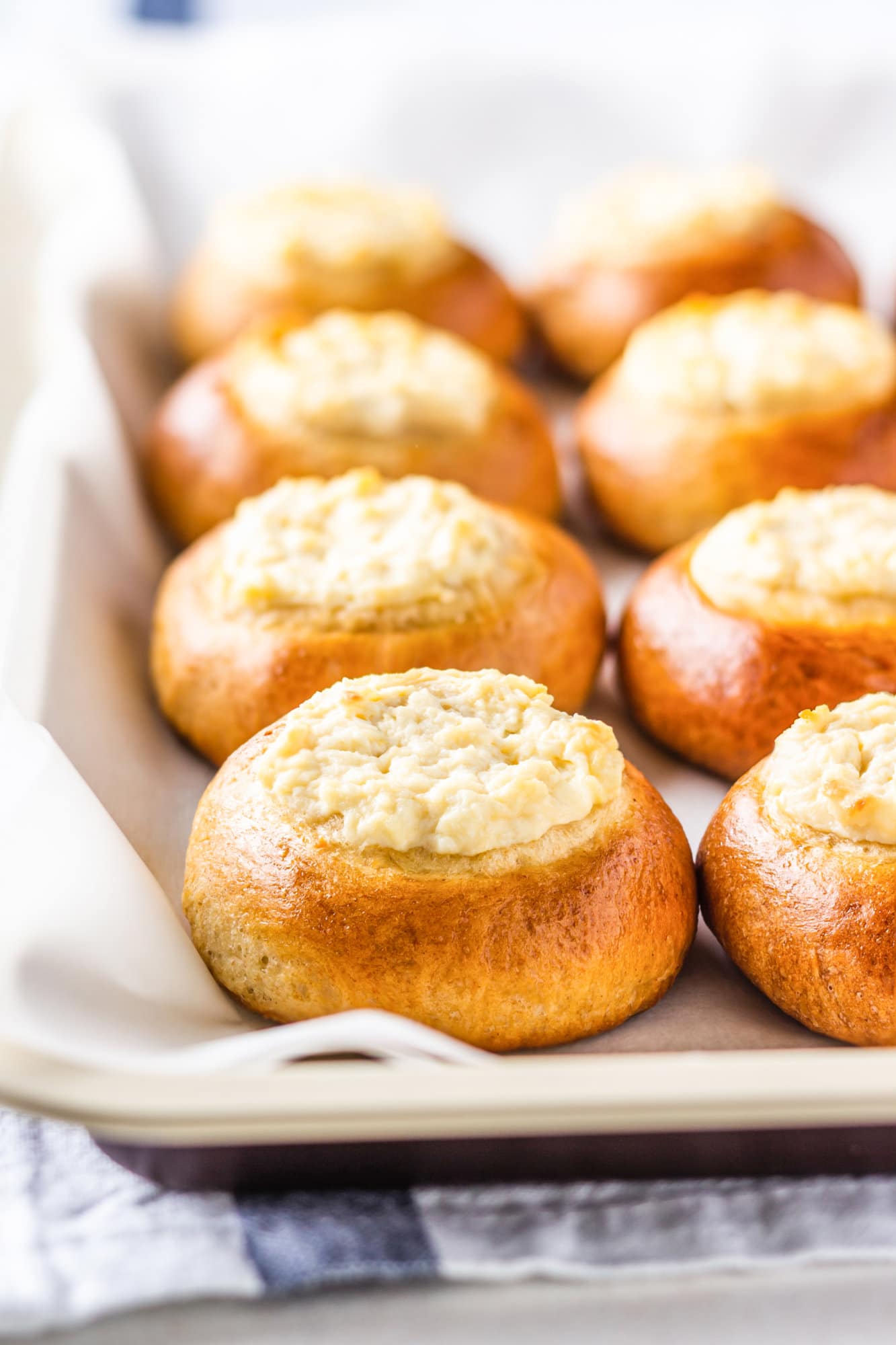 Russian sweet vatrushka buns on parchment paper on a baking sheet.