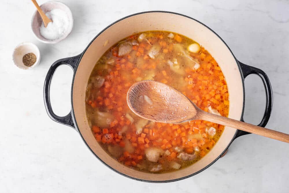 Cooking plov in a pot with a wooden spoon.