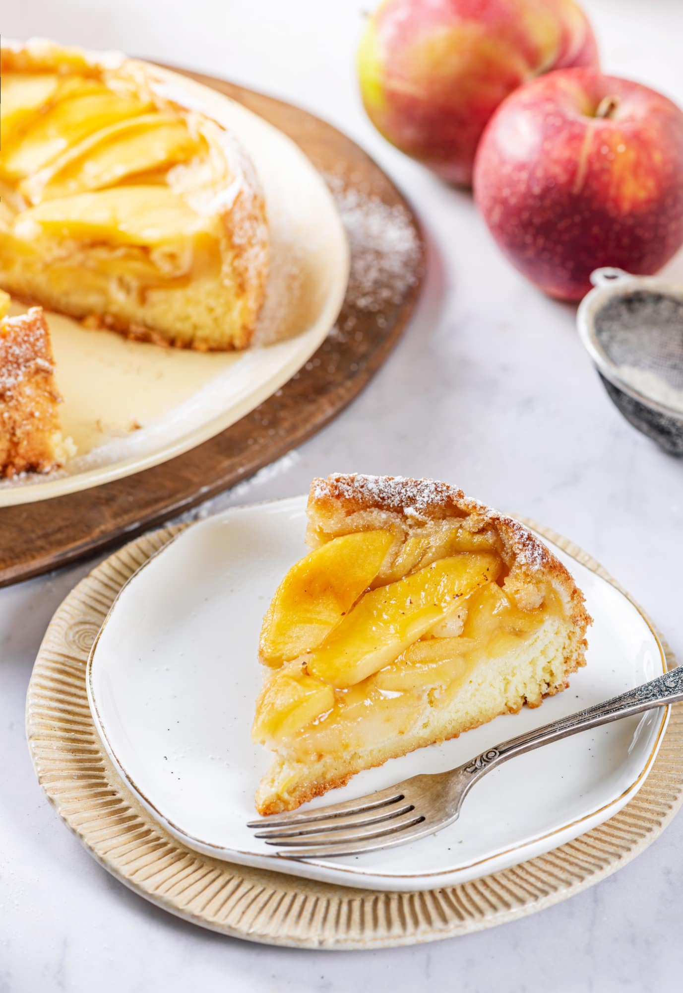 apple sharlotka cake baked and placed on a place with one slice cut on a separate plate near by. 