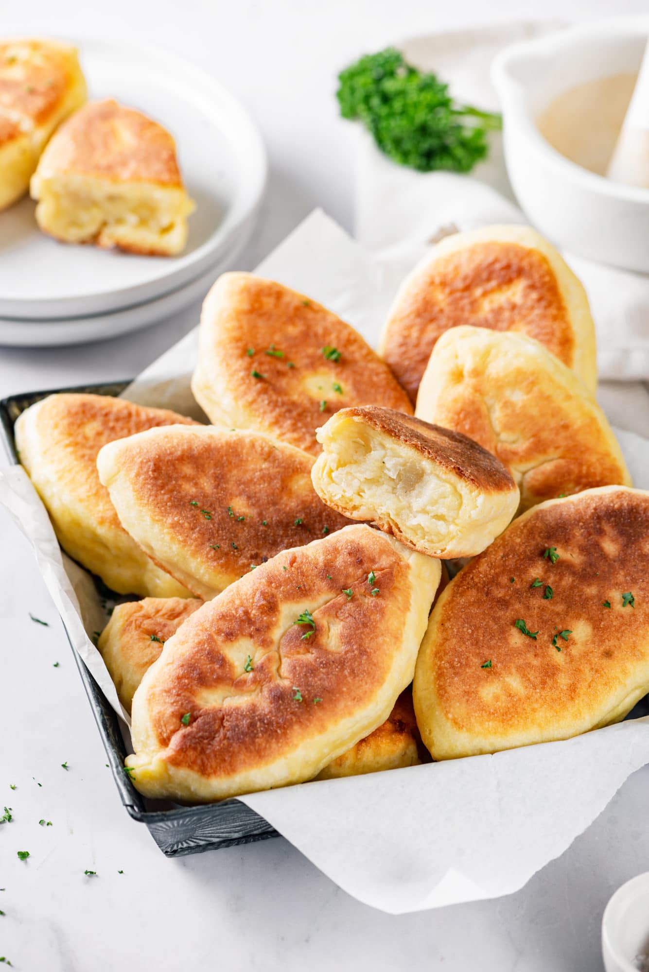 Piroshki with mashed potato filling in a tray lined with parchment paper.