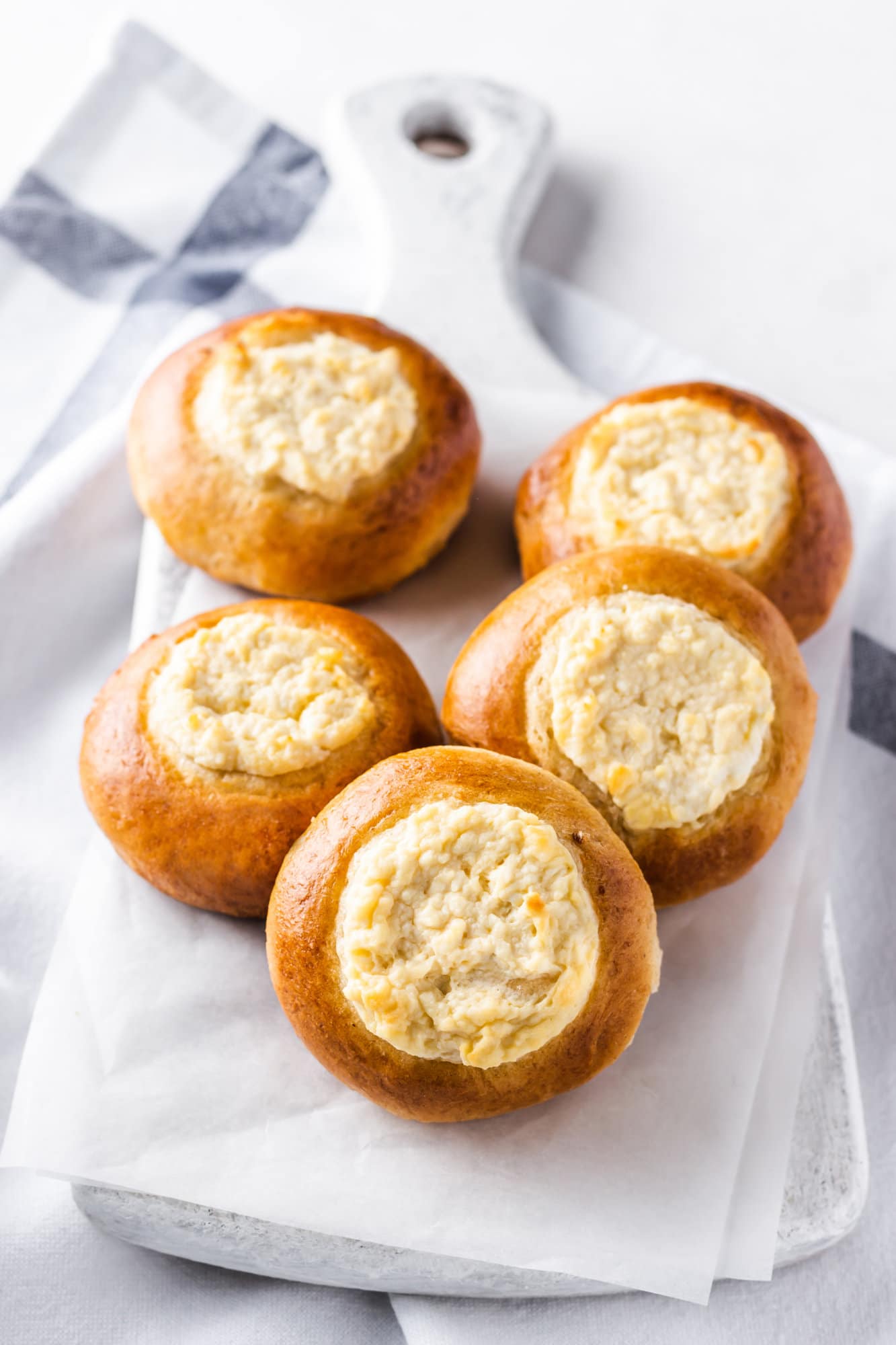 Russian sweet vatrushka buns on parchment paper and a white board.