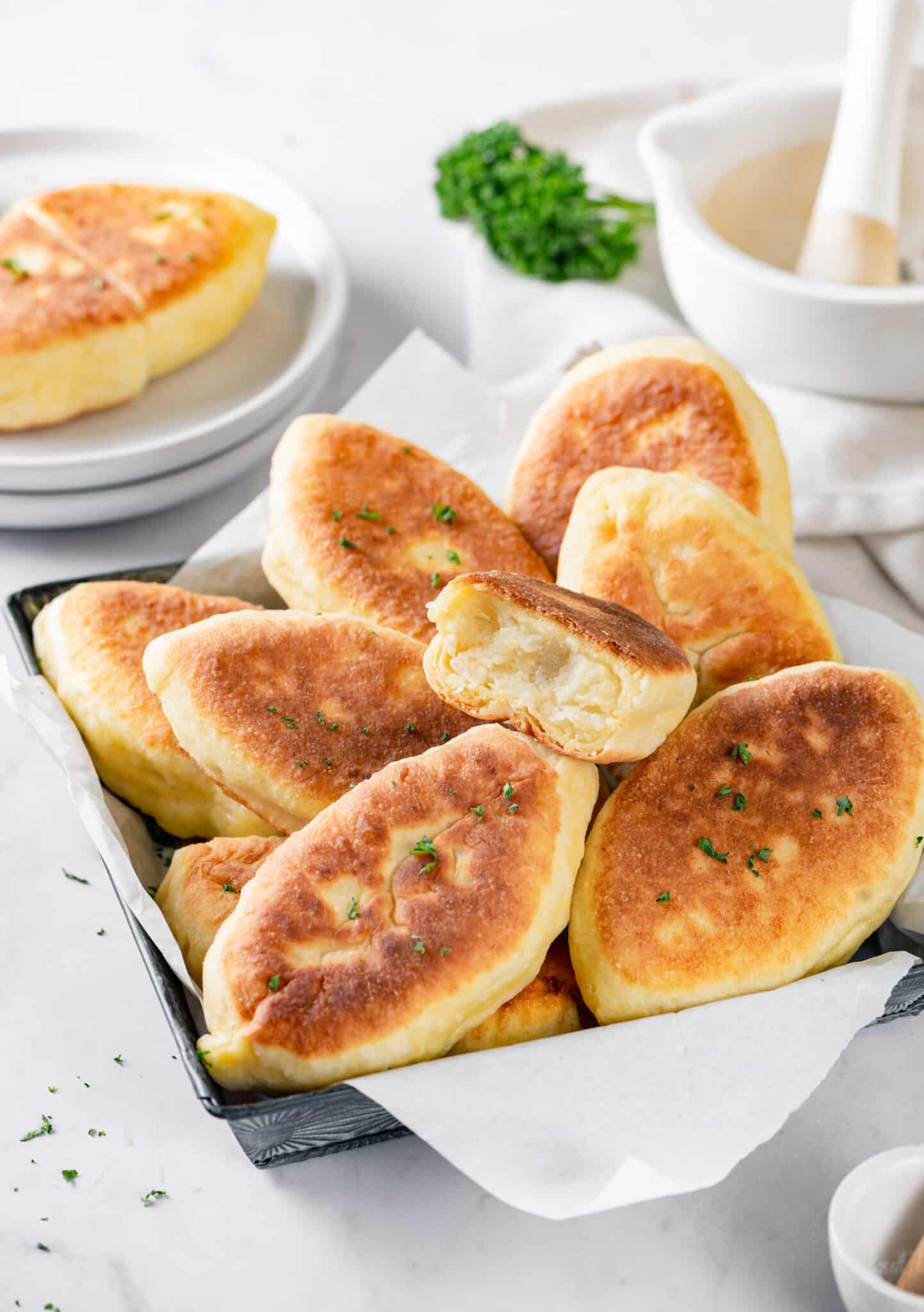 Piroshki with mashed potato filling in a tray lined with parchment paper.