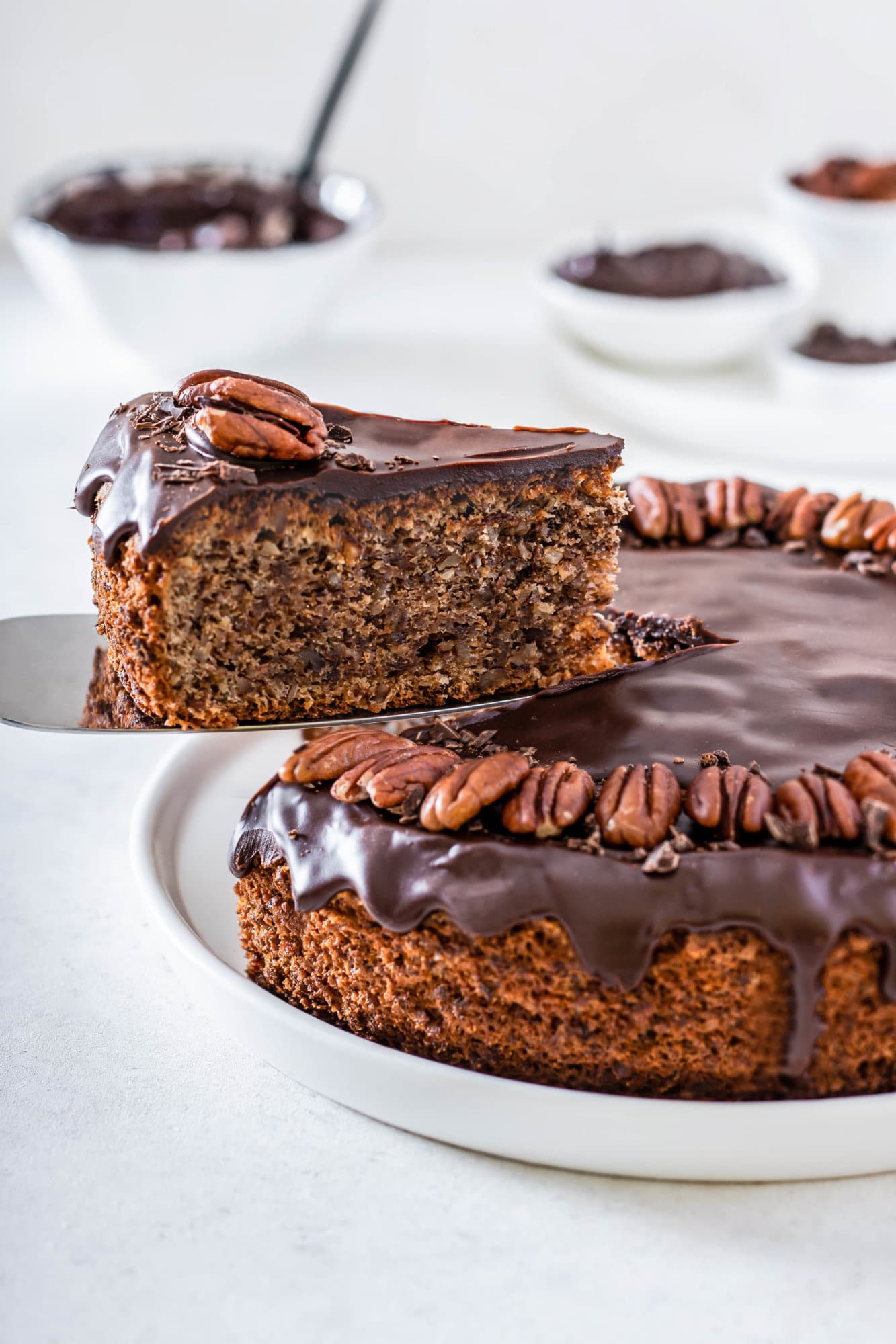 pecan-torte-on-a-white-plate-with-one-slice-lifted-on-a-spatula