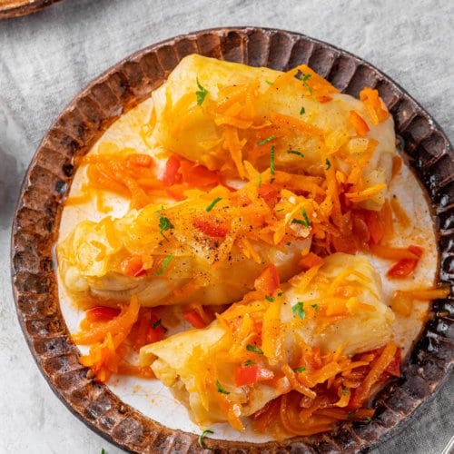 Cabbage rolls with vegetable sauce on a plate.