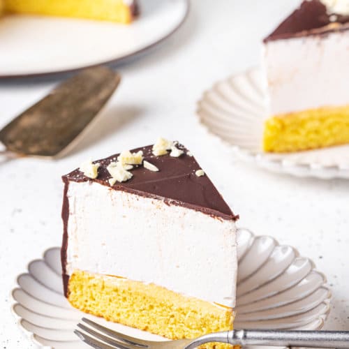 a slice of birds milk cake on a plate with a fork.