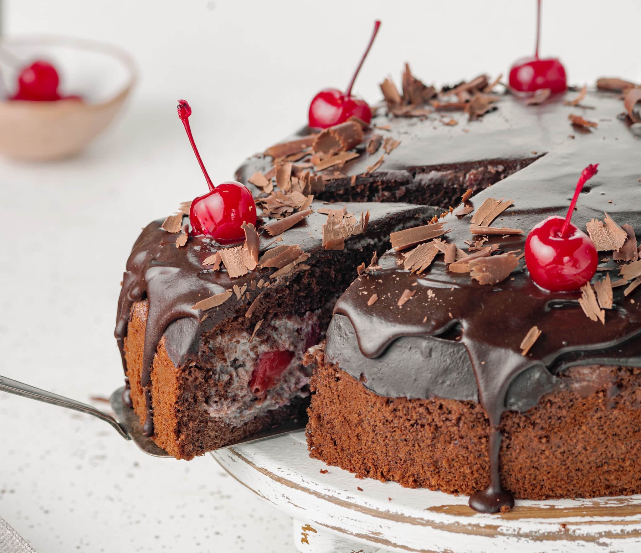 cherry-chocolate-cake-on-a-white-cake-stand-with-a-slice-of-cake-on-a-spatula