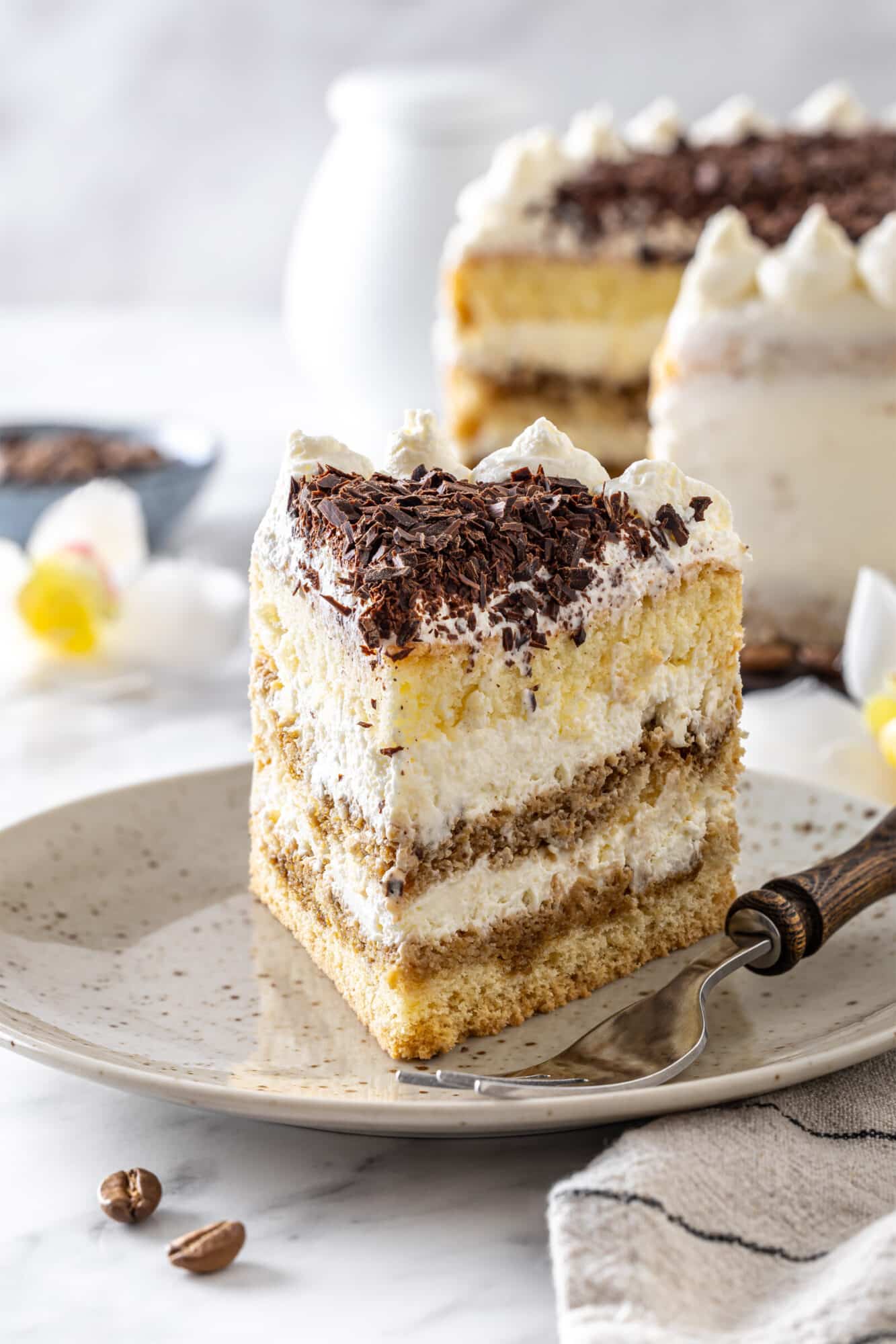 A slice of cake on a plate with chocoalte shavings on top for decor.