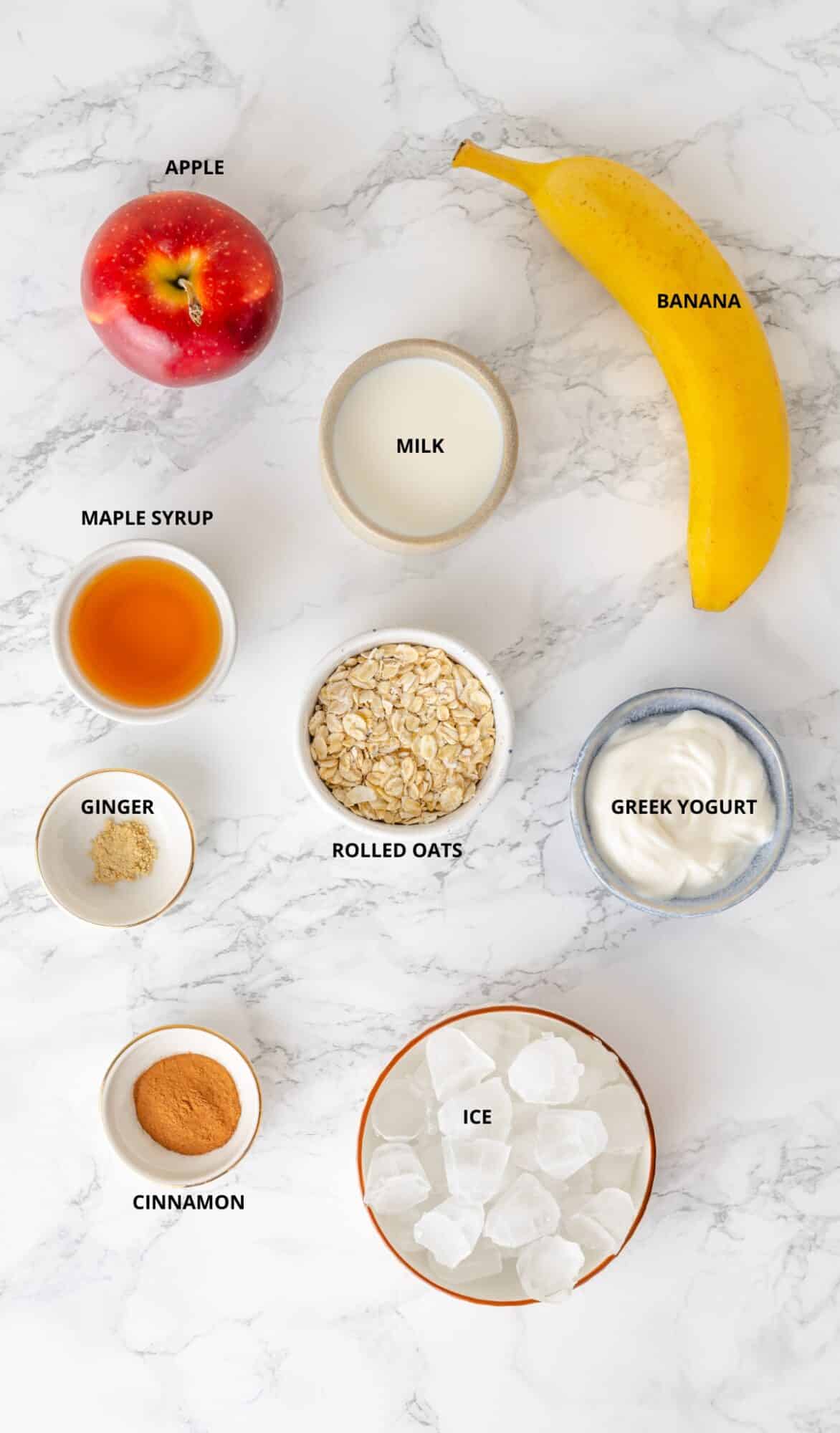 Apple pie smoothie ingredients- apple, banana, ice, milk, greek yogurt, maple syrup, ginger, cinnamon, and rolled oats.