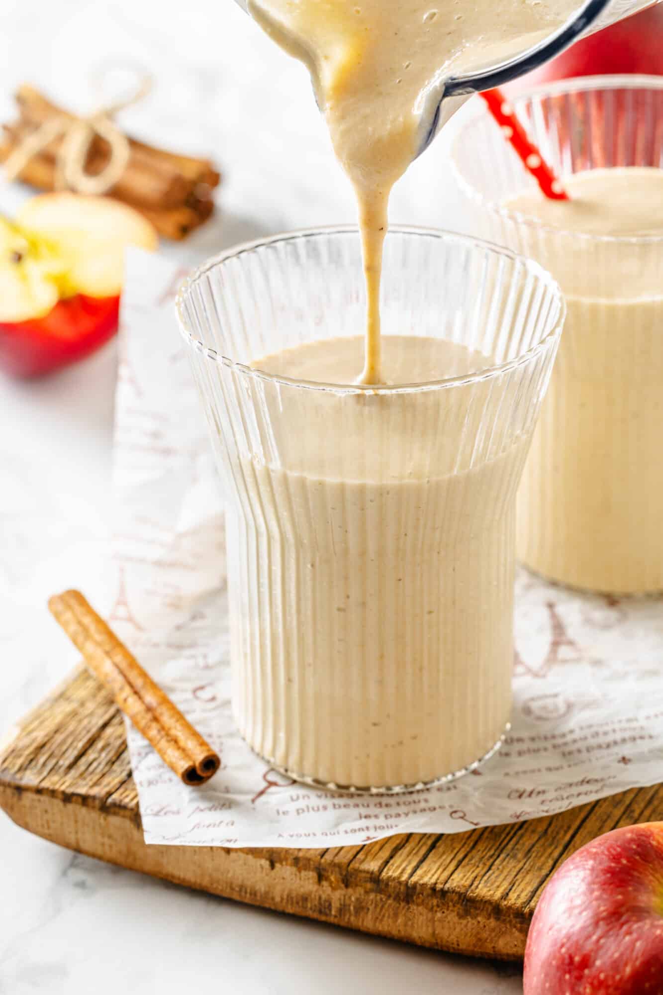 Apple pie smoothie being poured in a glass from a blender pitcher.