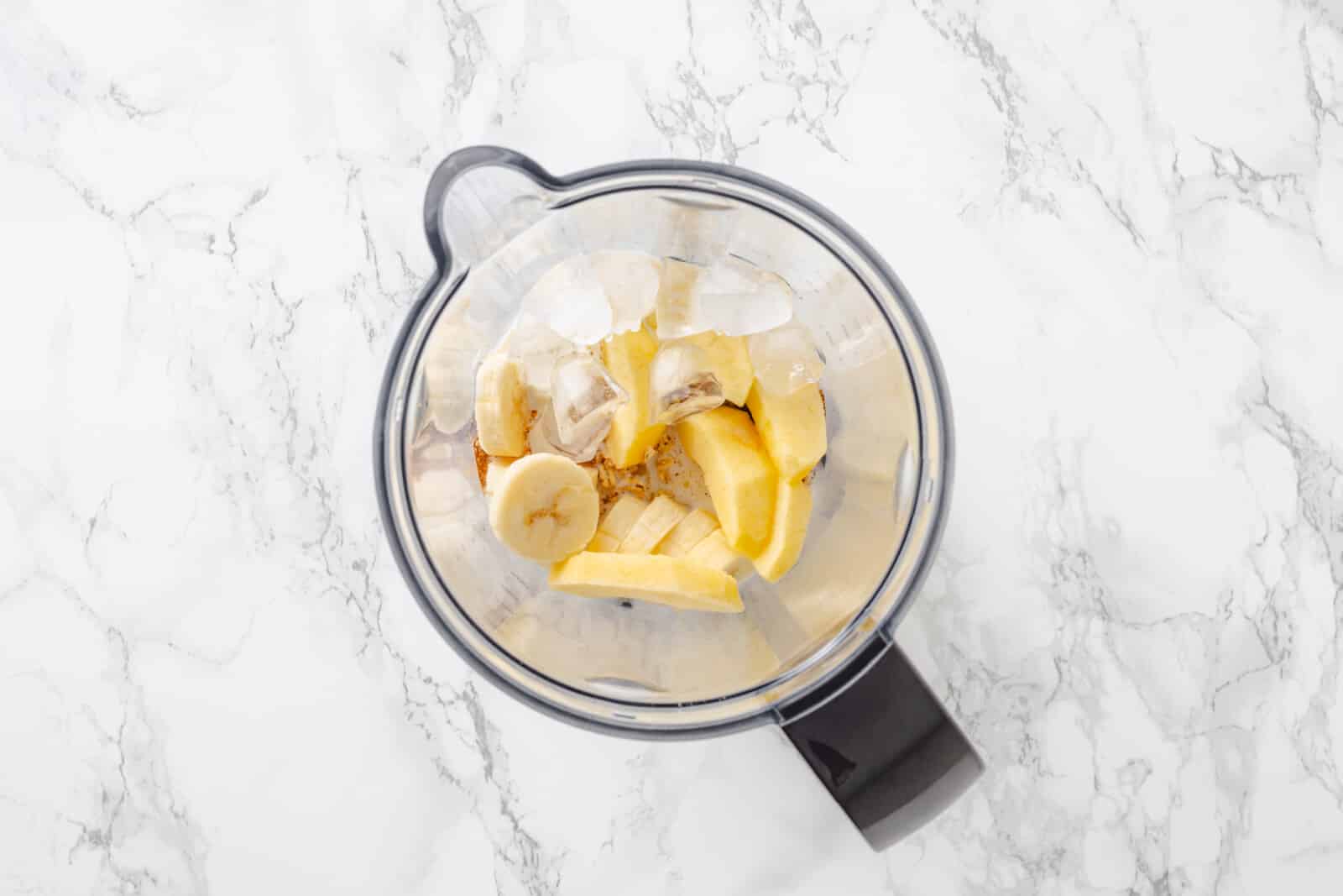 Apple pie smoothie ingredients in a blender pitcher.