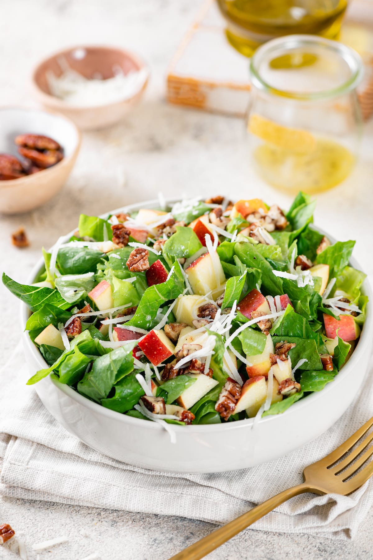 apple salad mixed with pecans green lettuce in a white bowl on white towel.