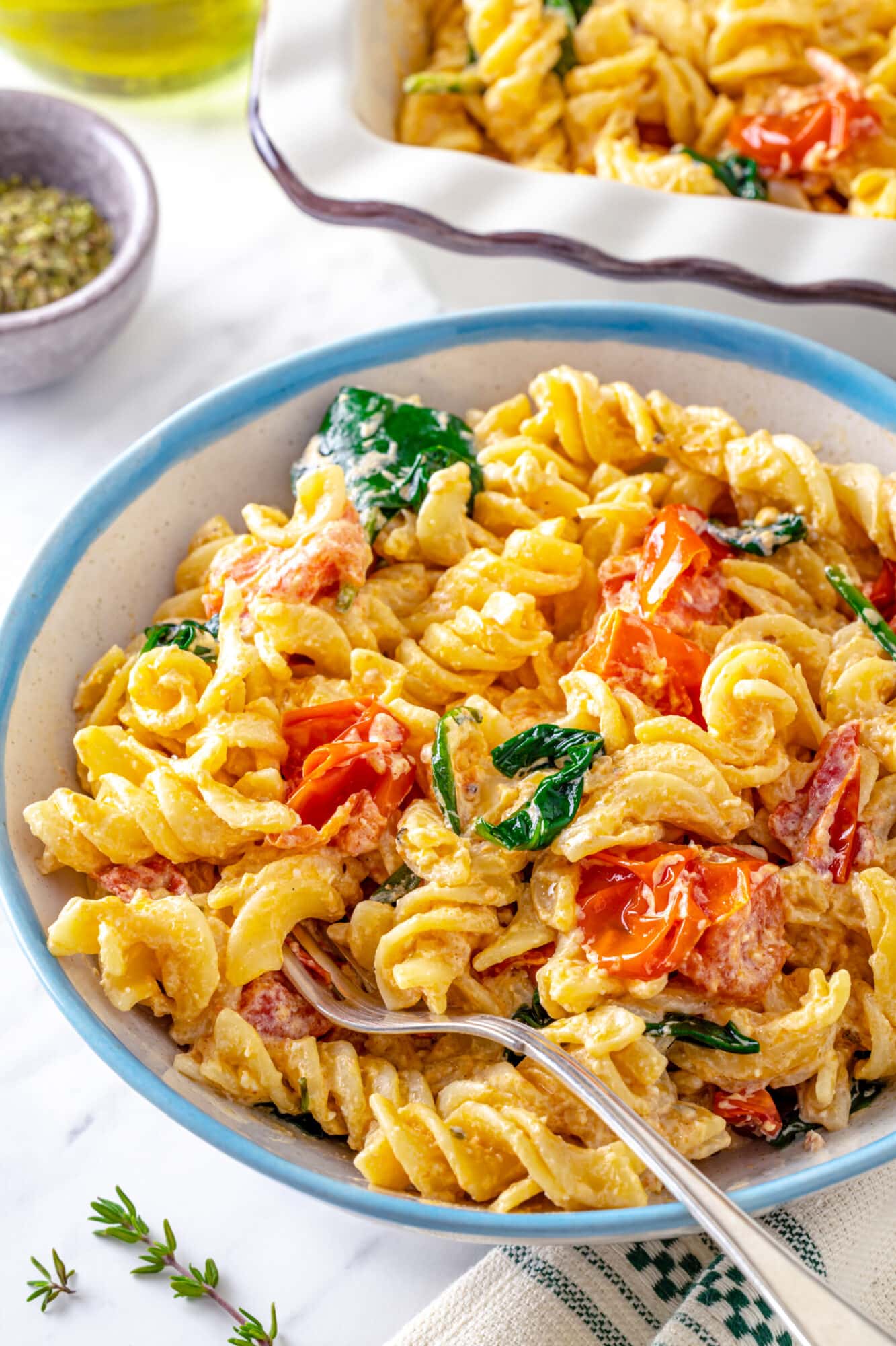 baked feta pasta with spinach and cherry tomatoes in a bowl with a spoon