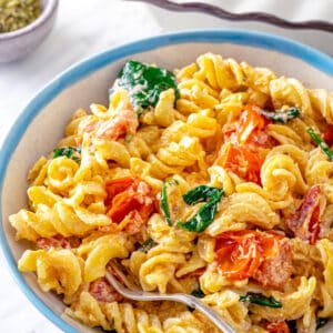 baked feta pasta with spinach and cherry tomatoes in a bowl with a spoon