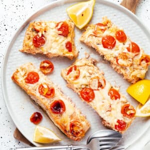 Oven baked salmon on a white plate with silverware.