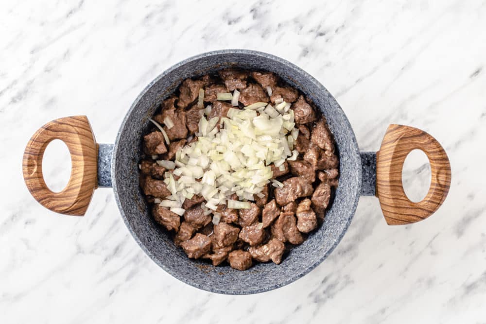 beef sauteed in a pot with onions.