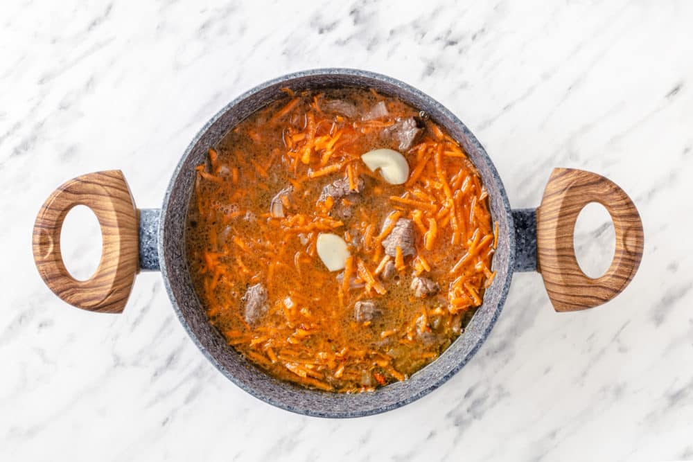 carrots garlic and beef cooking in a pot.