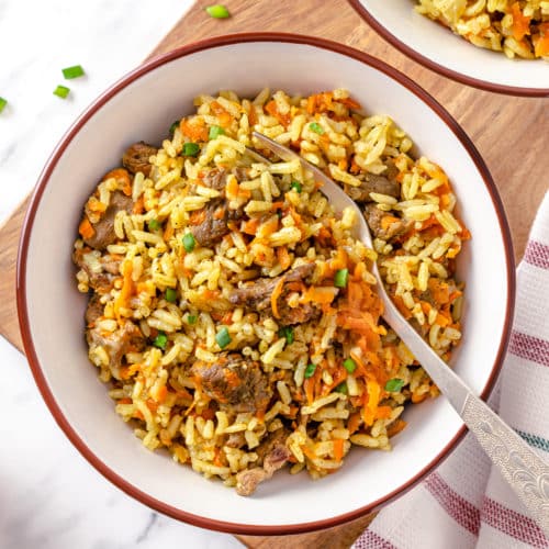 pilaf with beef in a white bowl with a fork.