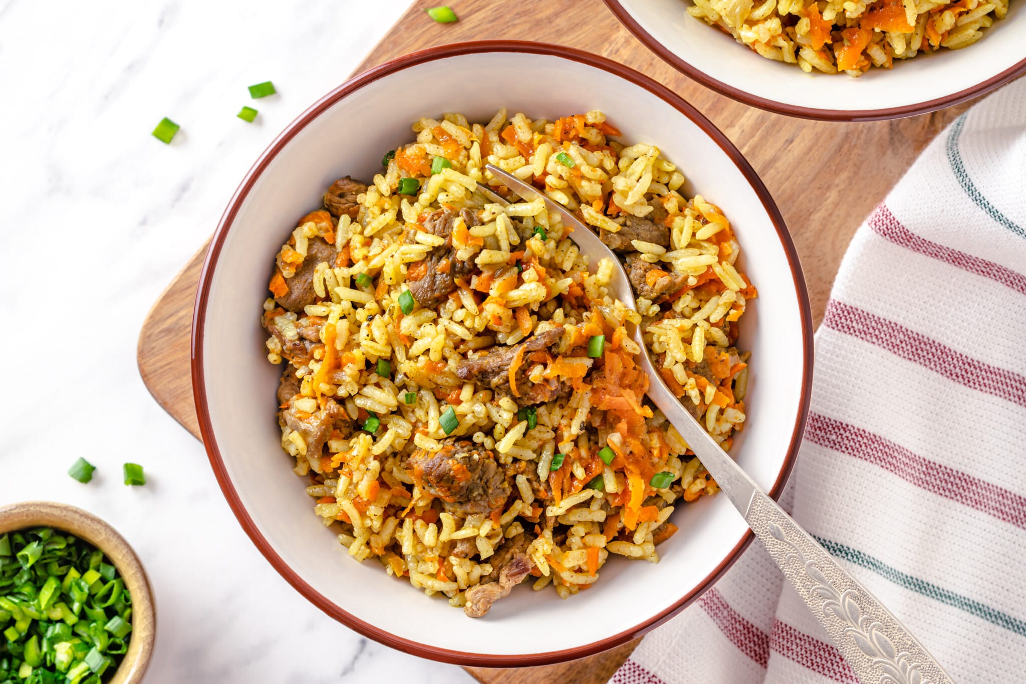 pilaf with beef in a white bowl with a fork.