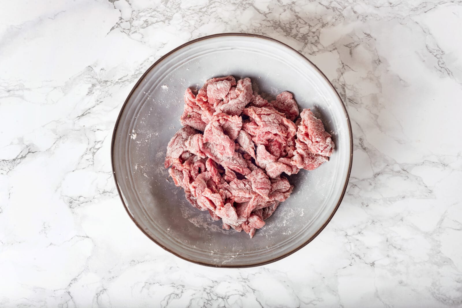 slices of beef coated in flour in a bowl