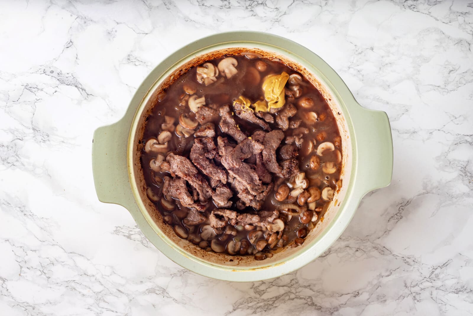 the beef strips added back into the bowl with the onions and mushrooms, along with the sauces and flavorings