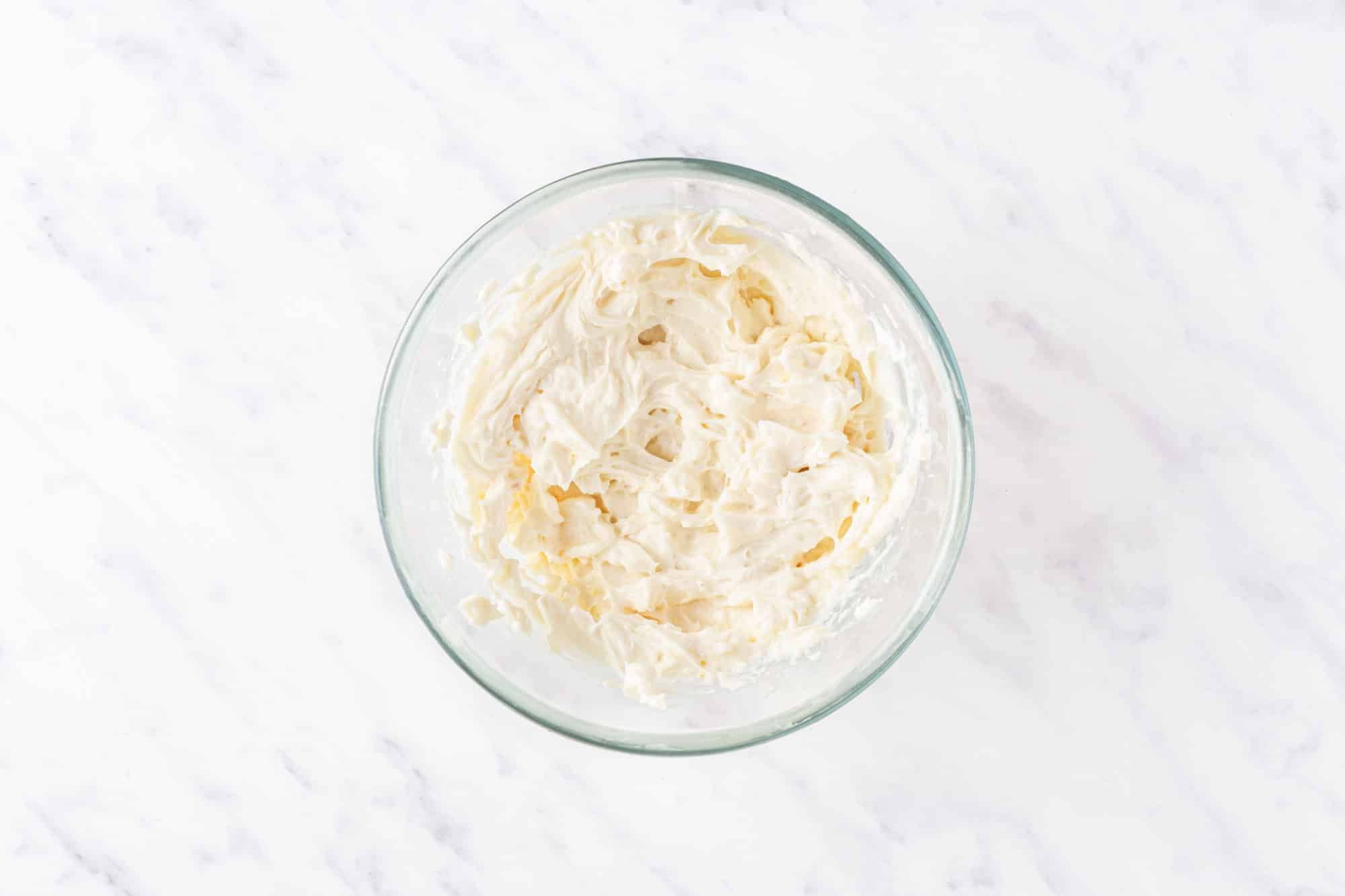 a glass bowl filled with blended cheesecake filling.