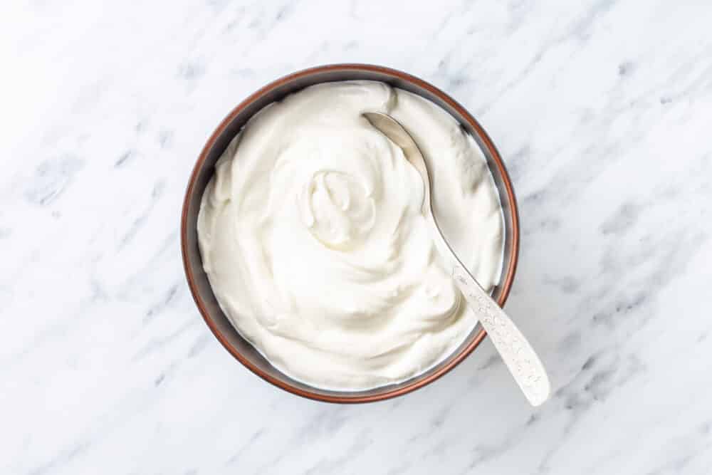 yogurt in a brown bowl with a spoon.