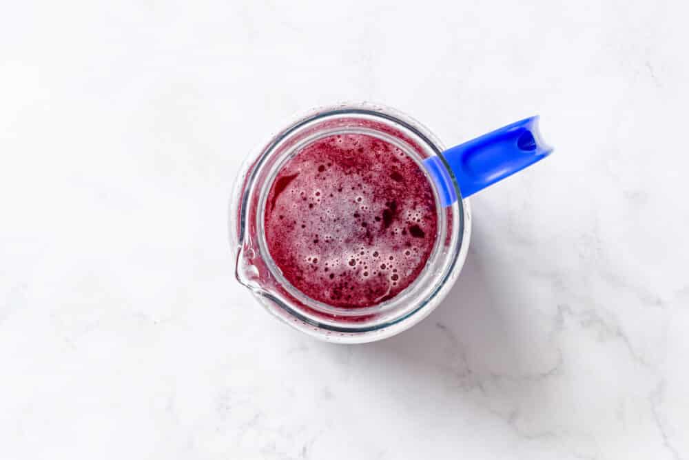 fresh boiled blueberry, mint, honey, lime juice and zest, in a clear pitcher with blue handle.