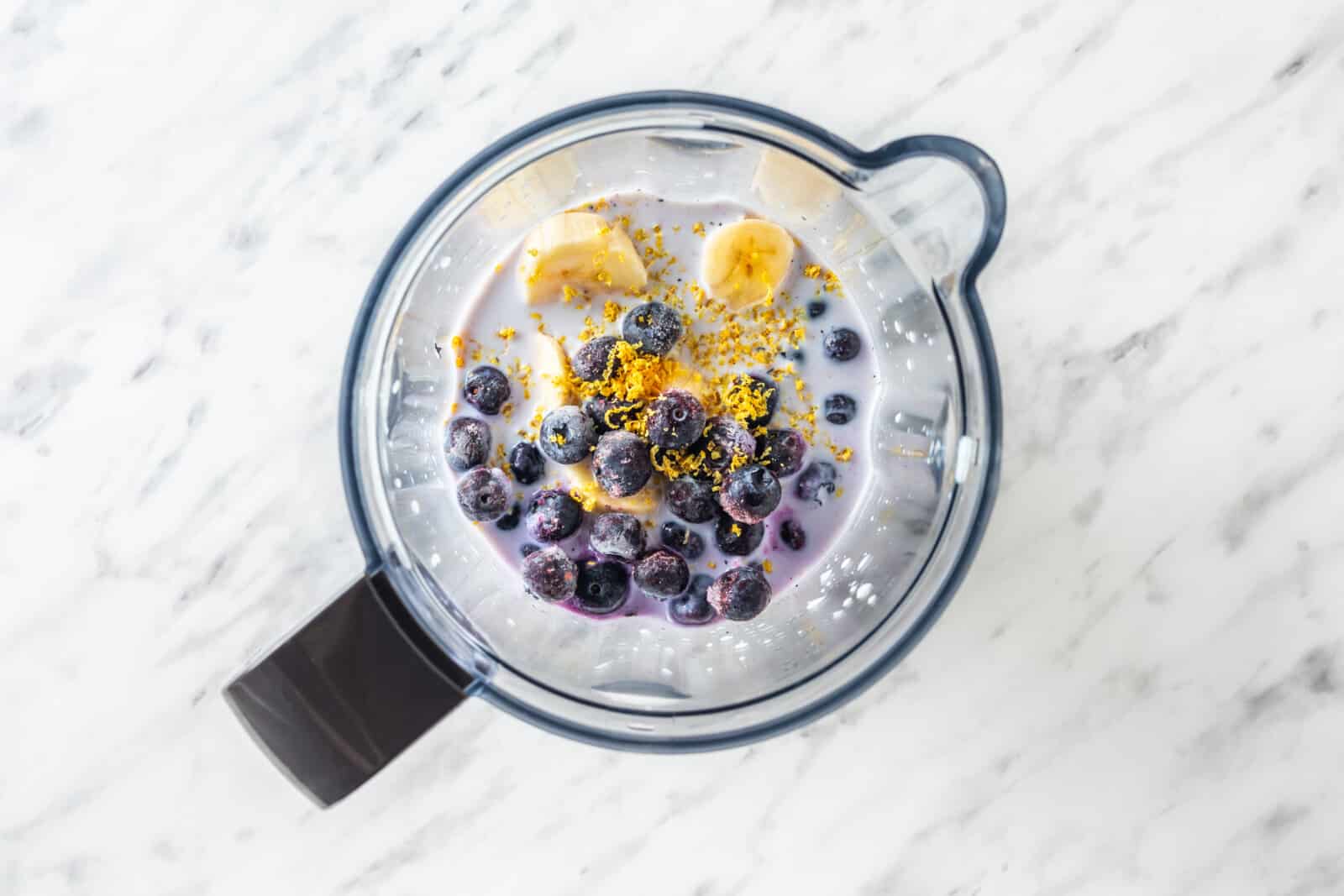 in a blender blueberries, lemon zest, banana, coconut milk and water.