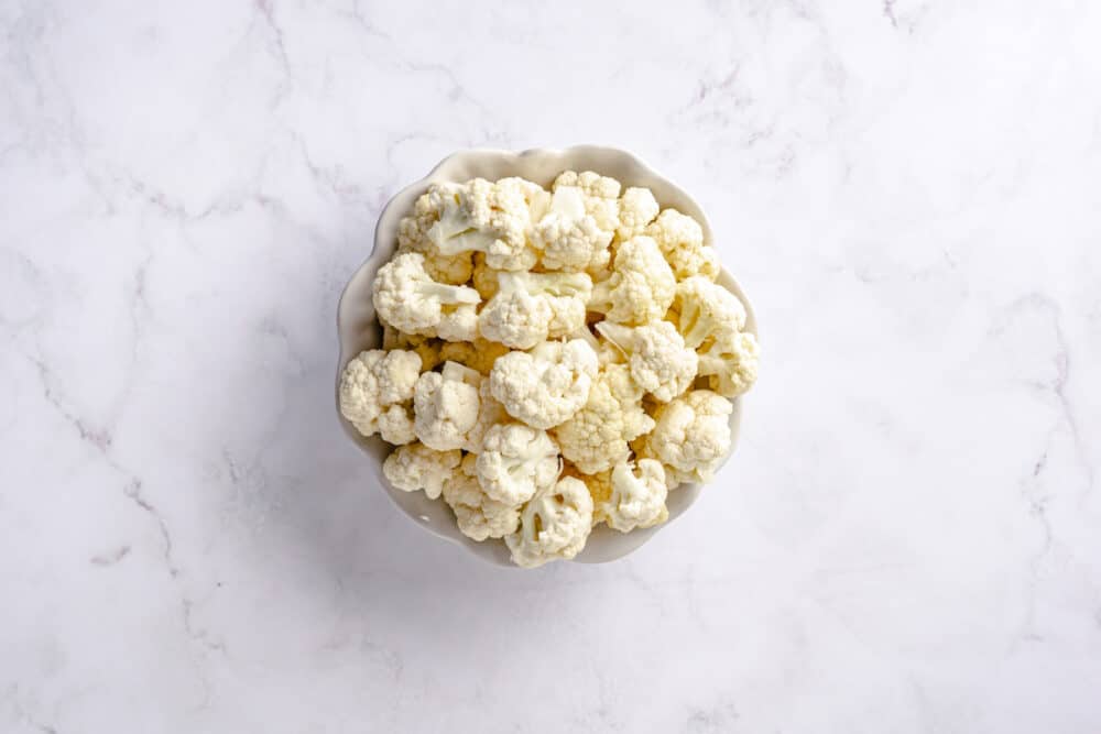 cauliflower florets in a white mixing bowl.