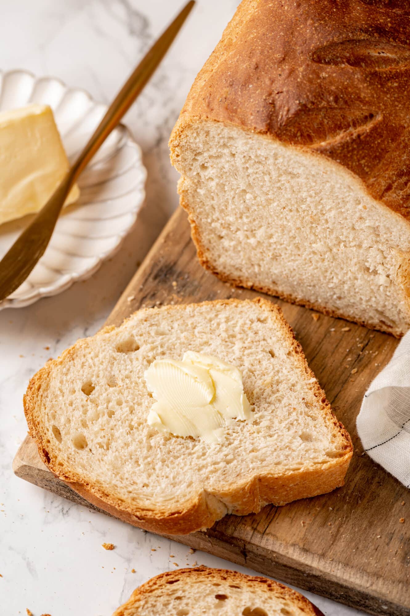 Buttered whole wheat bread slice on a wooden board.