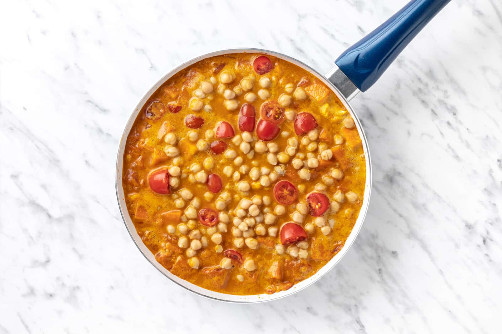 halved tomatoes and chickpeas in a skillet with curry.