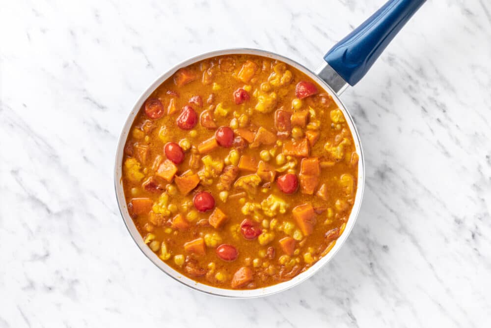 curry in a skillet cooking with tomatoes.