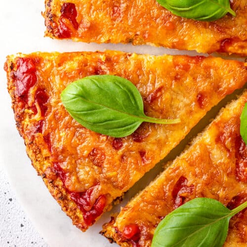 pizza cauliflower crust with fresh basil on marble background.