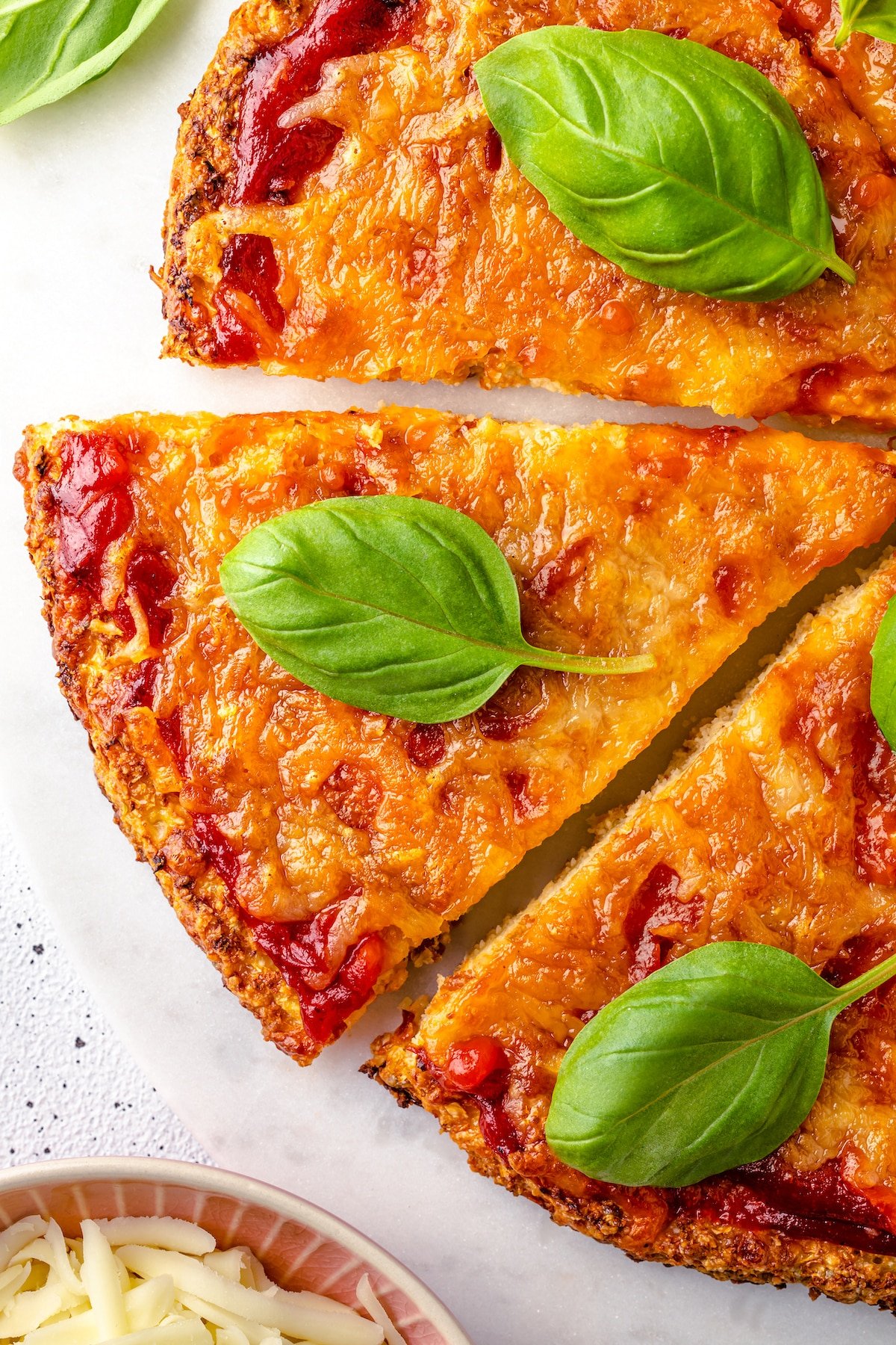 pizza cauliflower crust with fresh basil on marble background.