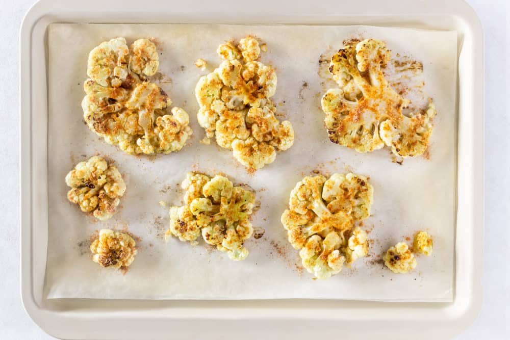 roasted cauliflower steak with spices and olive oil on a baking tray with parchment paper.