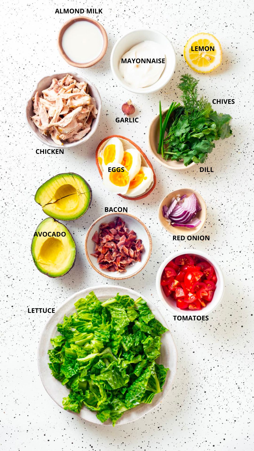 chicken cobb salad with dairy-free ranch ingredients- almond milk, mayonnaise, lemon, chives, dill, garlic, chicken, bacon, eggs, red onion, avocado, tomatoes, and lettuce.