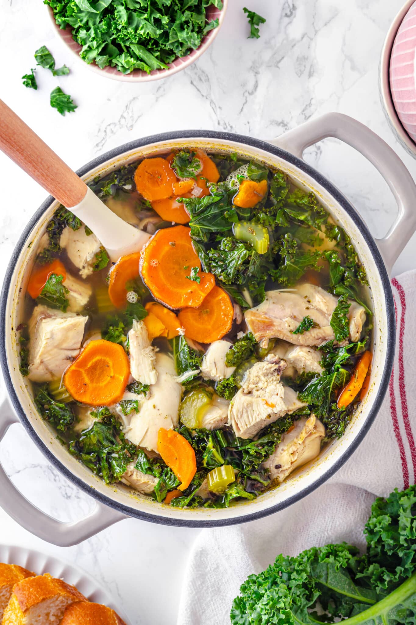 soup pot with chicken, carrots, celery, kale in stock.