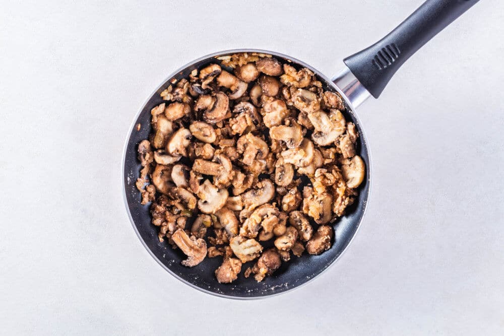 Mushrooms sauteing in a skillet.