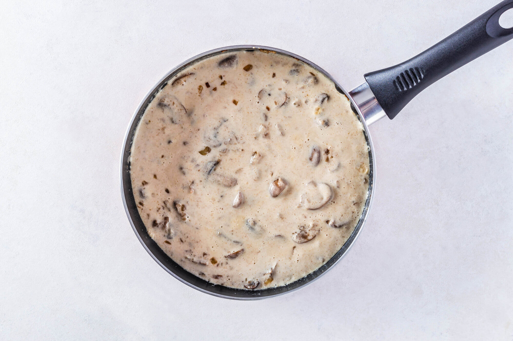 Half & half added to mushroom sauce cooking in a skillet.