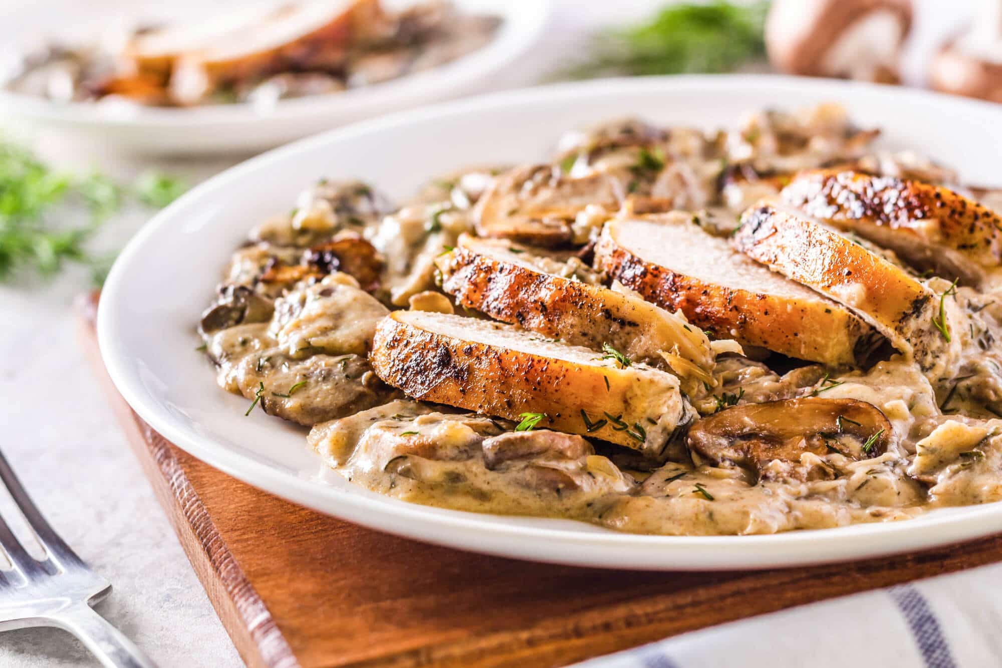 Sliced chicken atop a plate of mushroom sauce.